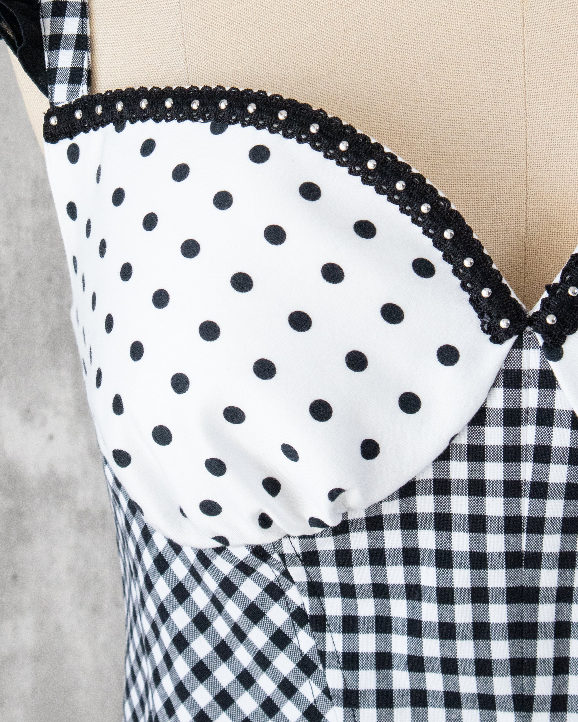 水玉とギンガム柄を組み合わせたビスチェの胸元クロースアップ。スタッズブレードのアクセント。