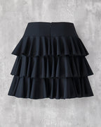 黒の３段ティアードフリルスカートのバックスタイル。コンシールファスナーあき。膝上丈。上品な光沢に肌触りの良い生地。