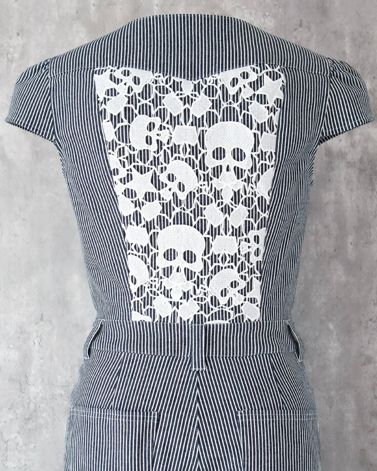 White skull lace detail on indigo hickory denim — Carla Jumpsuit by Atë, back panel close-up