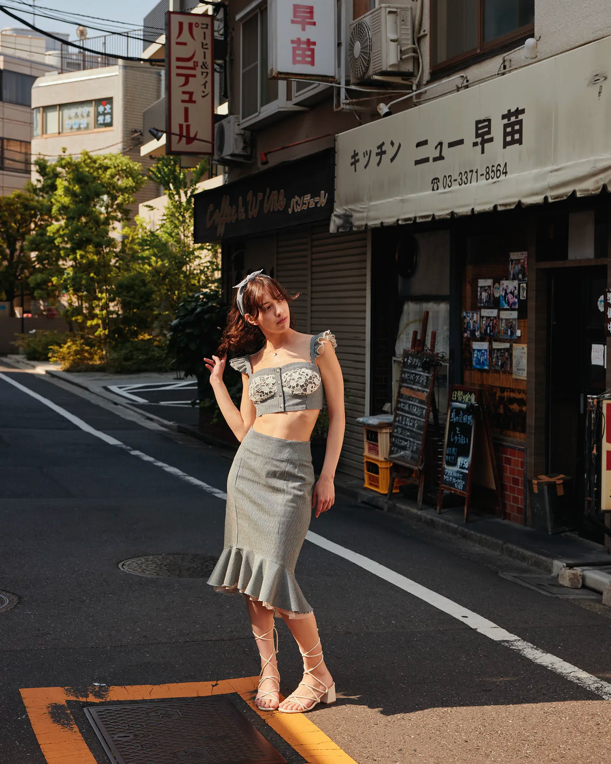 Model in the full Carla look — hickory denim bustier and high-waisted frill-hem skirt — on a Tokyo street — Carla by Atë
