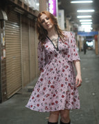 Model in a pale dusty pink skull print chiffon dress, walking in an arcade street — Lola Dress by Atë